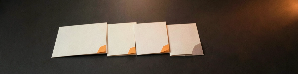 Photograph of four blank sheets of paper laid out in a row like steps, with small tabs at their edges