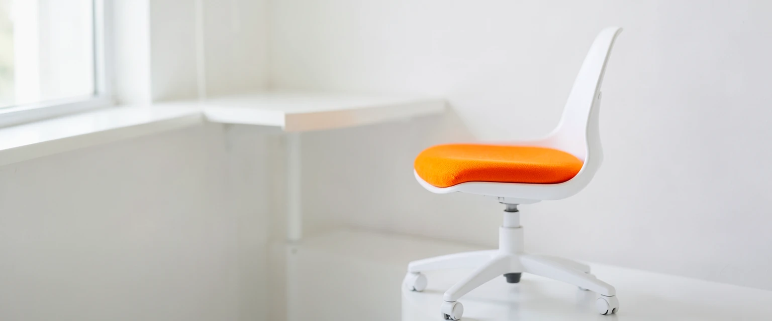 Photograph of a small white swivel chair with an orange seat cushion