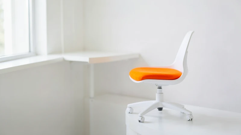 Photograph of a small white swivel chair with an orange seat cushion