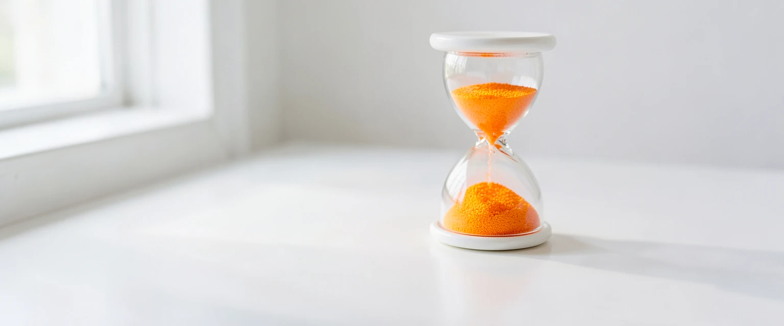 Photograph of a white hourglass filled with orange sand