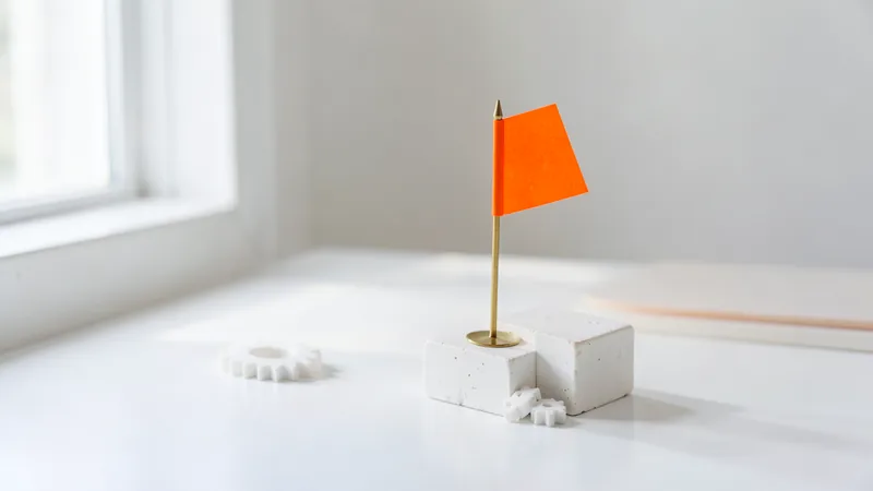 Photograph of a small orange flag beside two white gears