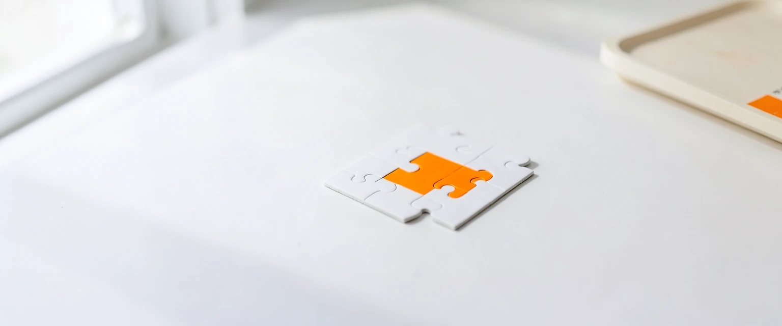Photograph of a white four-piece puzzle with one orange piece
